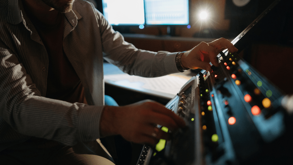 Music producer adjusting analog gear in recording studio.