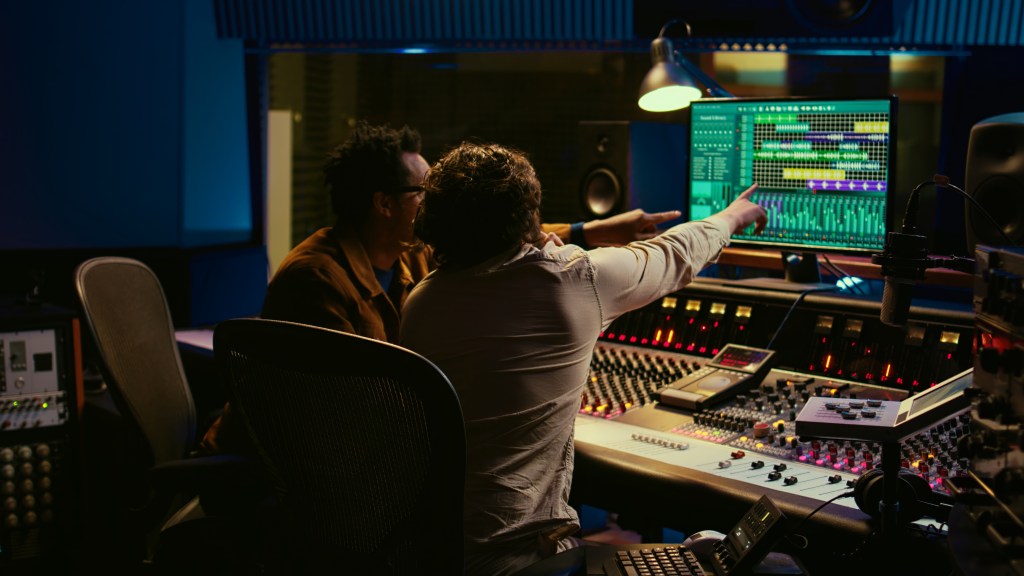 Music producers reviewing vocal tracks in a DAW during a studio session.