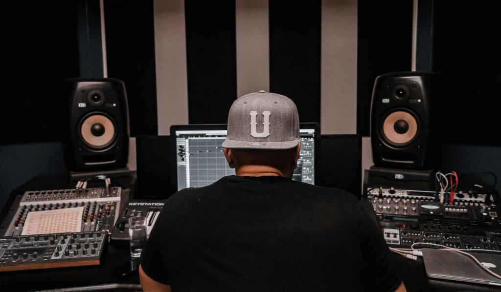 Music producer working in a home studio mixing vocals on a computer.