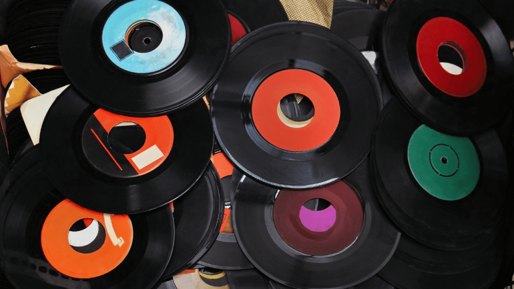 Old vinyl records and cassette tapes stored without labels, representing voices used without consent or fair compensation in free AI vocal tools